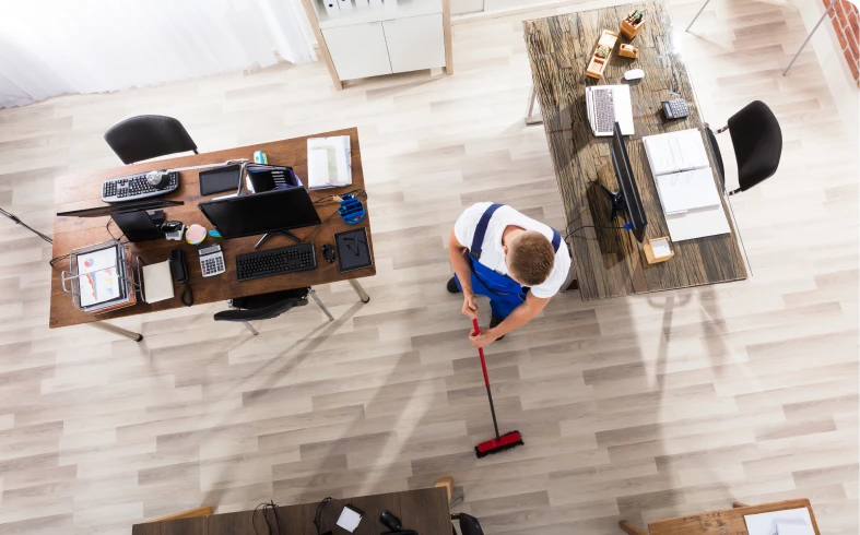 Office worker sweeping hardwood floor